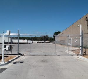 A chain link aluminum cantilever gate in front of an industrial complex