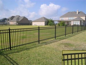 A flat top ornamental iron fence stretched across a backyard with a closeup of the flat top