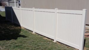A section of a privacy vinyl fence in a diagonal shot near the side of a house