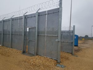 A metal high security fence with coils of barb wire 