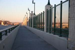 A square mesh panel system fence stretched across the side of a bridge