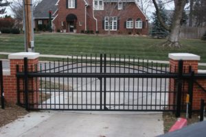 An iron ornamental over arch cantilever gate set on a residential street in front of a residential driveway