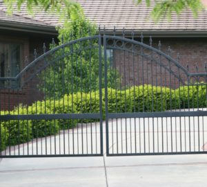 A spear top over arch ornamental swing gate in front of a curving driveway