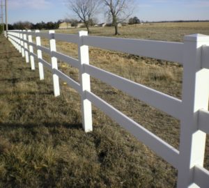 A white vinyl ranch rail stretching off into the distance on a field