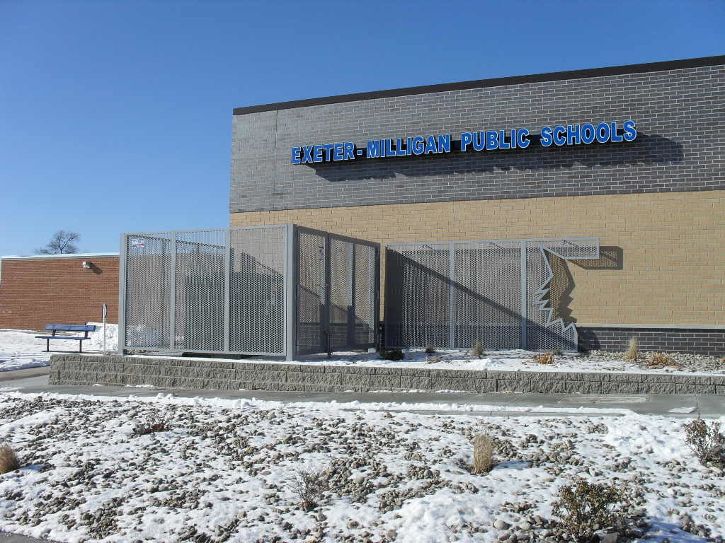 A custom aluminum perforated panel screen system installed at Exeter-Milligan Public Schools. It has half of a timber wolf's face cut into the end of the screen