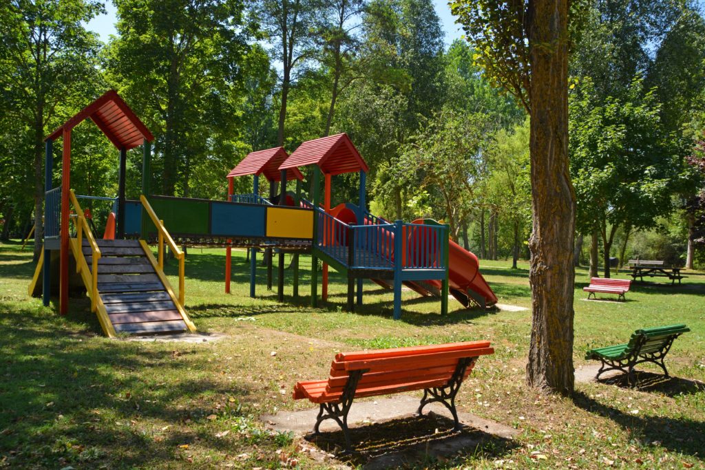 A park bench overlooking a play structure in primary colors