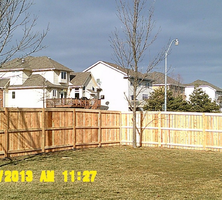 A custom privacy wood fence with a picket cupboard and 3 rails
