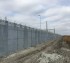 A shot of a long stretch of high security fence with ballistic characteristics. This fencing also has barb wire and razor wire installed on top.