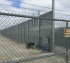 A view of a ballistic high security fence through some chain link mesh