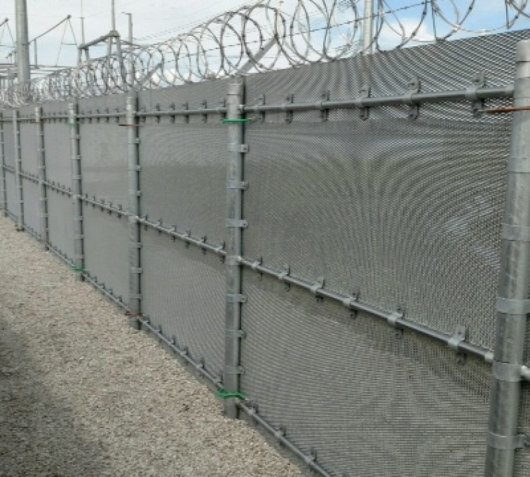 Several sections of high security ballistic fence with barb wire and razor wire installed on top