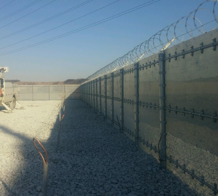 Ballistic high security fencing with no visibility and coils of razor wire on top for extra security