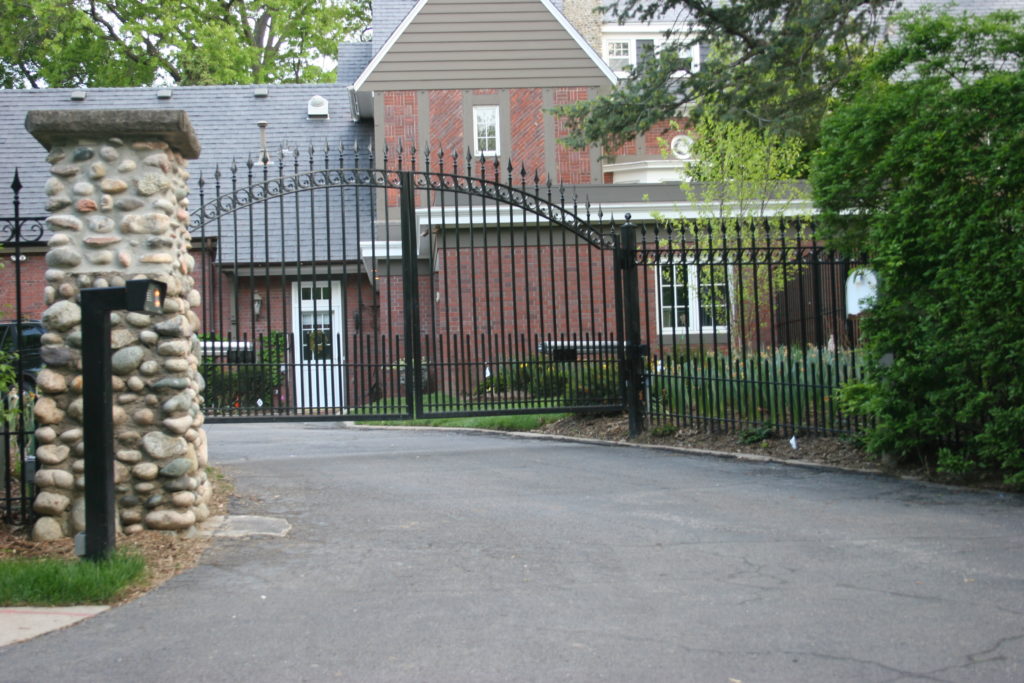 Over arch decorative driveway gate with gate opener. Rochester fence company fence contractors Minnesota gates automation residential commercial