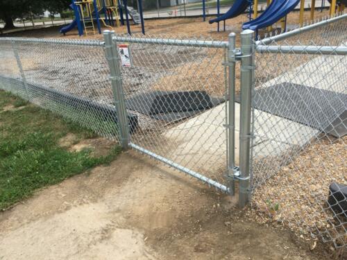 4 - 6 foot tall grey chain link fence enclosing playground