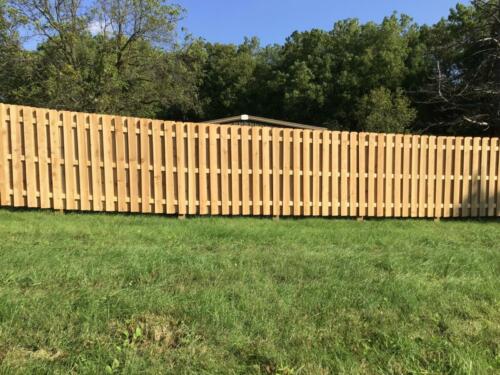 6-8 foot tall shadow box wooden fence enclosing a yard