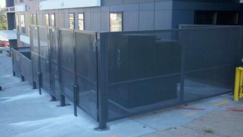 6 - 8 foot black woven and welded wire fence creating an enclosure around outdoor power boxes on cement