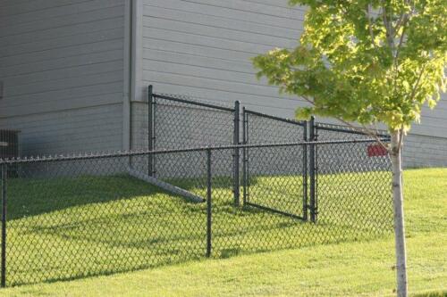 6 - 8 foot tall grey chain link fence following the perimeter of a building
