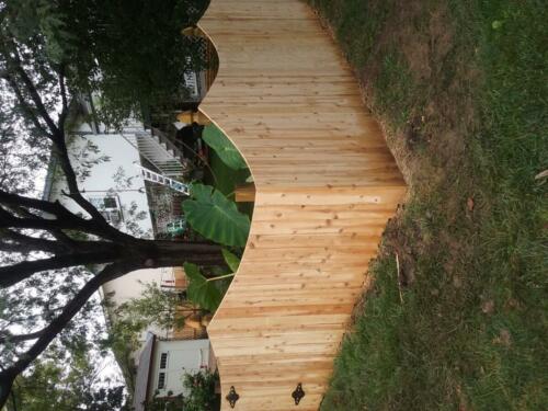 4-6 foot tall underscalloped pattern privacy wooden fence with similarly styled single swing gate