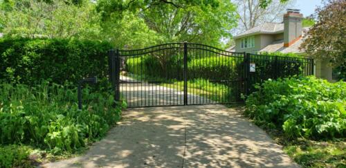  6 - 8 foot tall black arched automated  gate with access control speaker box