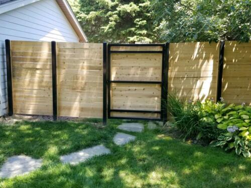 6-8 foot tall horizontal wooden fence with black metal fence posts and a similar single swing gate