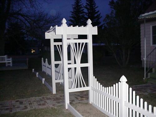 3-5 foot tall underscalloped white fence with a decorative 5-7 foot white gateway (no gate)