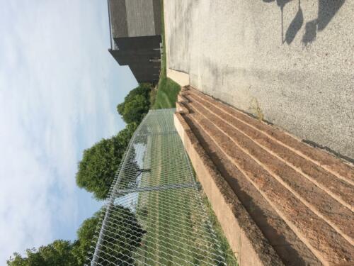 4' grey vinyl chain link fence atop a large retaining wall. 