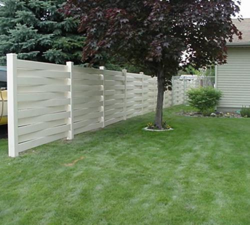 6-8 foot tall basket weave white vinyl fence partially enclosing a yard