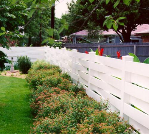 3-5 foot tall basket weave white vinyl fence partially enclosing a yard while running alongside trimmed bushes