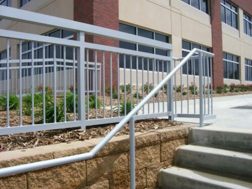 3 - 4 foot tall simple grey hand rails alongside outdoor stone staircase