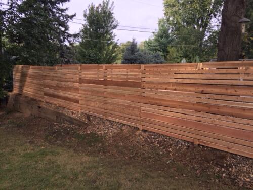 6-8 foot tall horizontal wooden fence with hidden off-colored posts