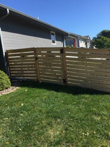 6-8 foot tall horizontal semi-private wooden fence with hidden off-colored posts at slightly varying height due to uneven terrain