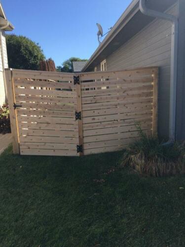 6-8 foot tall horizontal wooden fence with vertical posts and similarly styled single manual swing gate