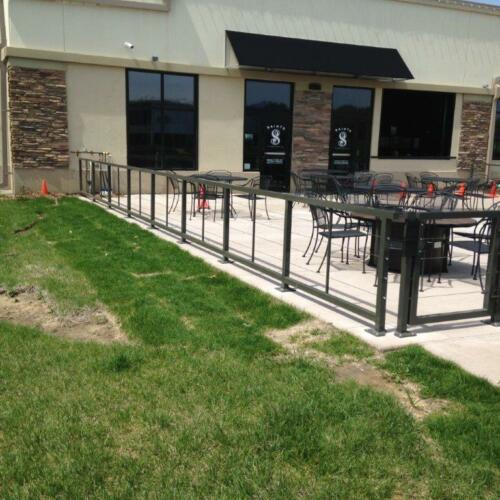 3 - 4 foot tall black metal handrails enclosing outdoor dining area