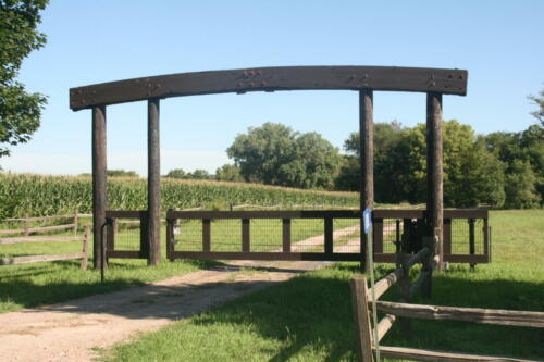3-5 foot tall wooden automated gate with an arch overhang about 7-9 feet tall