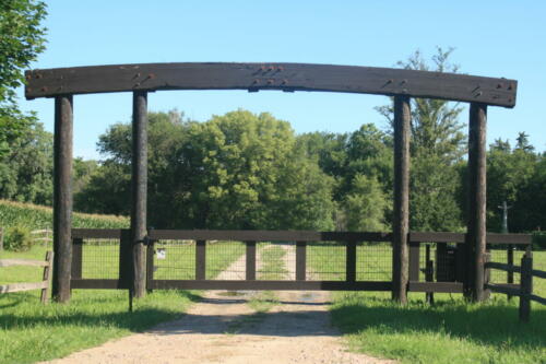 3-5 foot tall wooden automated gate with an arch overhang about 7-9 feet tall