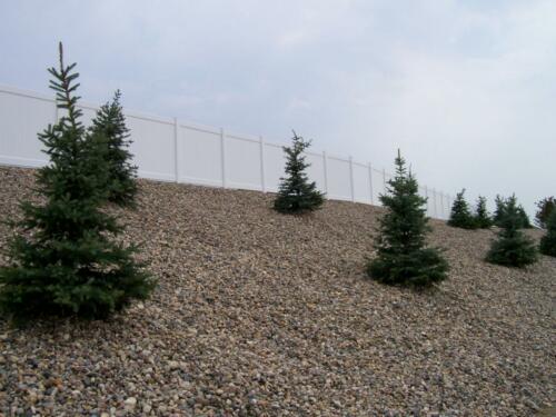 4 - 6 foot tall white vinyl fence going along the top of a hill