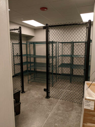 American Fence Company chain link fence acting as a shed with shelving units inside