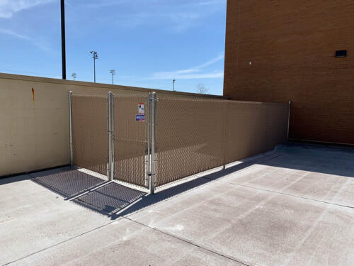 Perimeter chain link fence securing an area to the side of a building