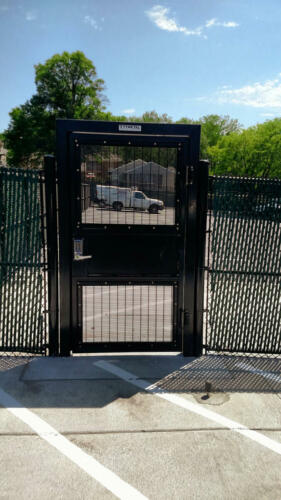 6 - 8 foot black access control security door attached to a green 6 foot fence