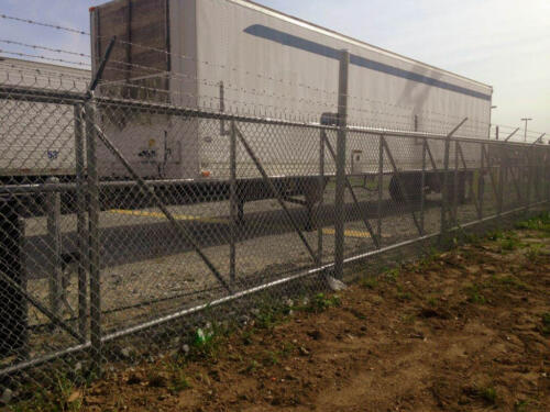 6-8 foot grey high security chain link fence with 3 - 5 lines of barb wire at the top