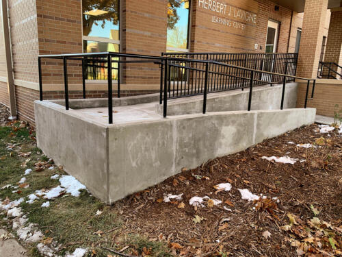 4 - 5 foot tall simple black railing around large outdoor accessibility ramp