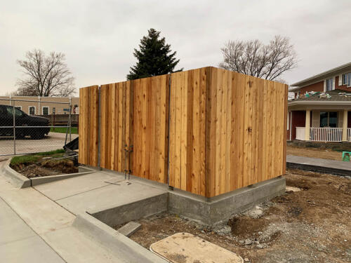 6 - 8 foot tall wood fencing with two swing gates atop a cement surface creating an enclosure