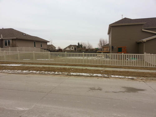 4-6 foot off-white vinyl picketed fence with a 2-5 inch gap between each fence plank