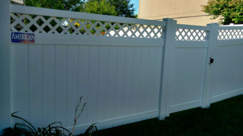 6-8 foot tall white vinyl privacy fence with a crisscross stitched pattern on the top before connecting to a straight white horizontal board that connects that a fence posts 