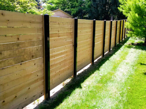 6-8 foot tall horizontal wooden fence with black metal fence posts