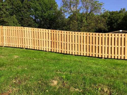 6-8 foot tall shadow box wooden fence enclosing a yard