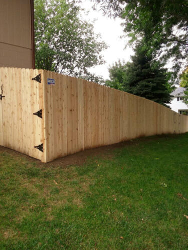 5-7 foot tall wooden privacy fence enclosing a yard with similarly styled single swing gate