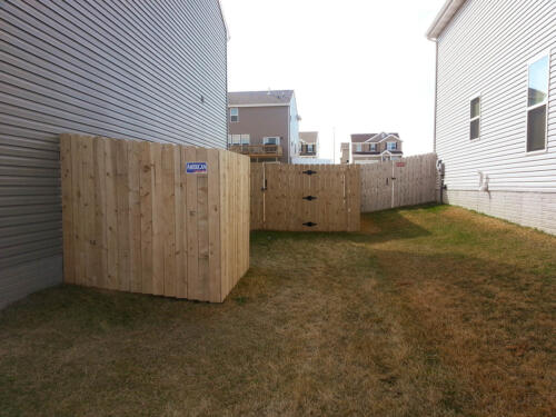 5-7 foot tall wooden privacy fence enclosing a yard with two to three similarly styled single swing gate