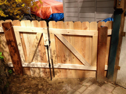 4-6 foot tall wooden privacy fence with interior wooden reinforcement on double swing gate