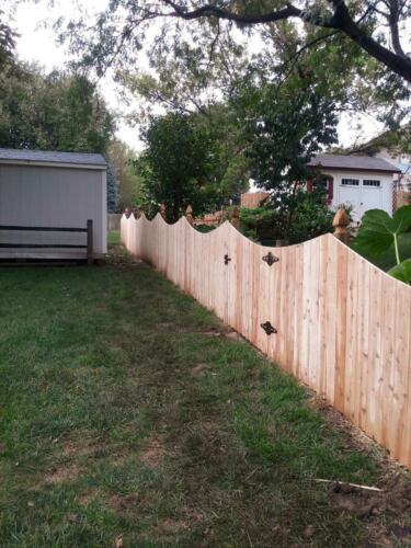 6-8 foot tall underscalloped pattern privacy wooden fence with similarly styled single swing gate