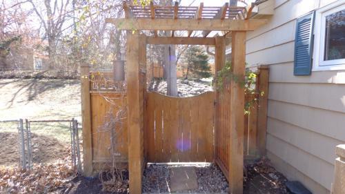 4-6 foot tall arched wooden gate with an overhang above the entrance